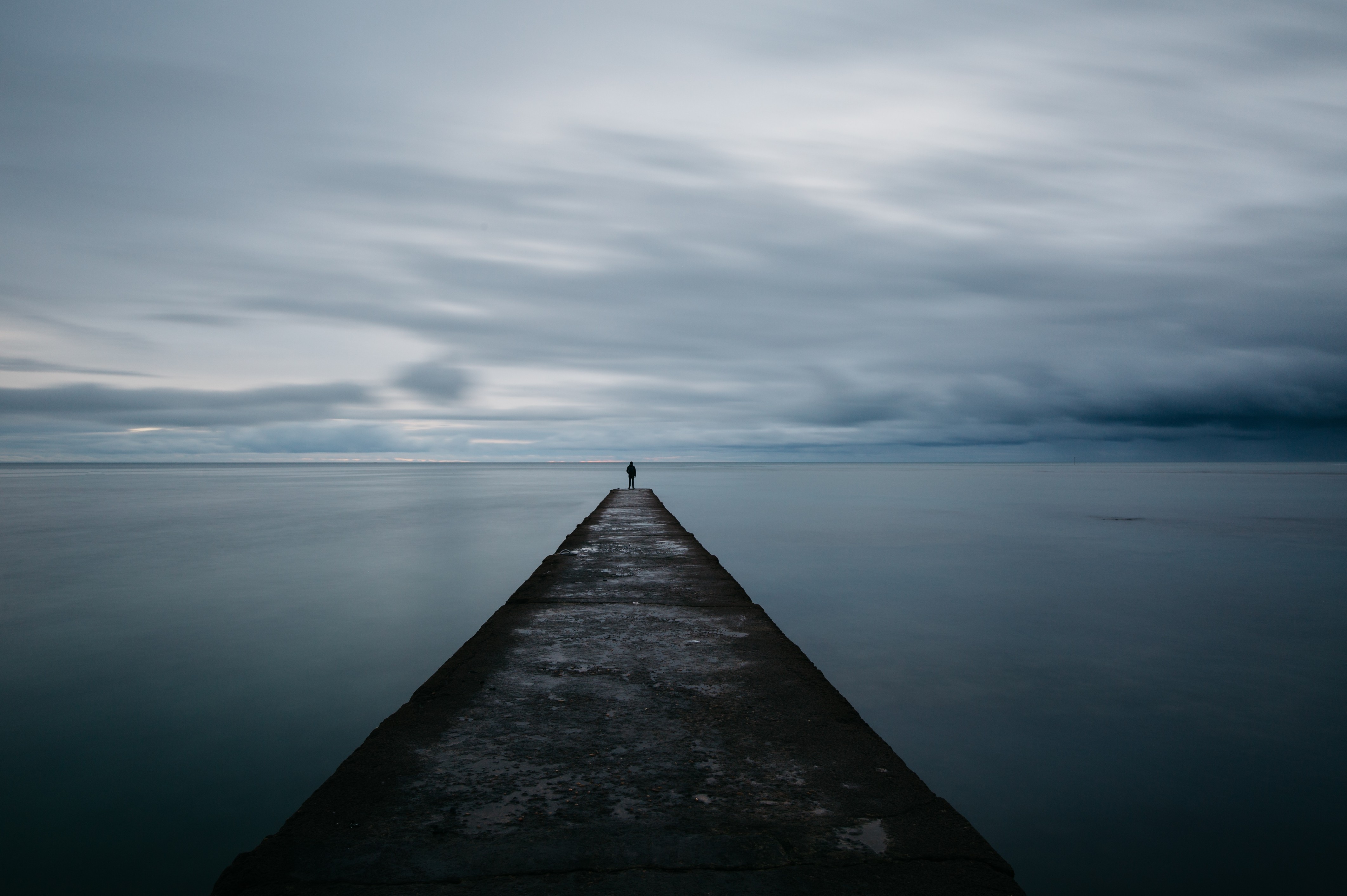 man-lonely-pier-horizon-dark-clouds-sea